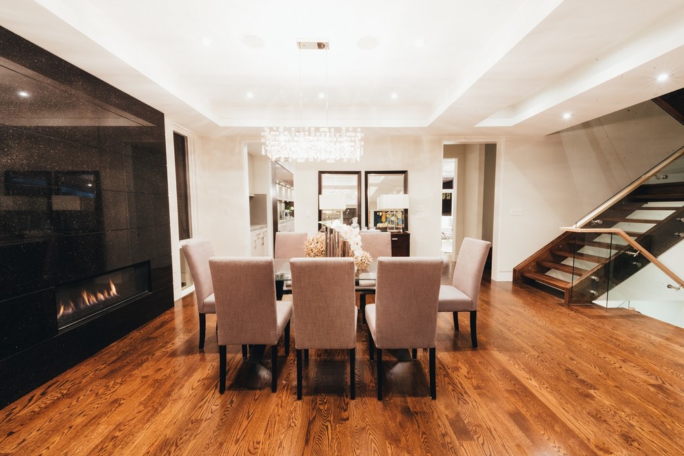 Photo of a large modern separate dining room in Toronto with white walls, medium hardwood floors, a tile fireplace surround, brown floor and a ribbon fireplace.