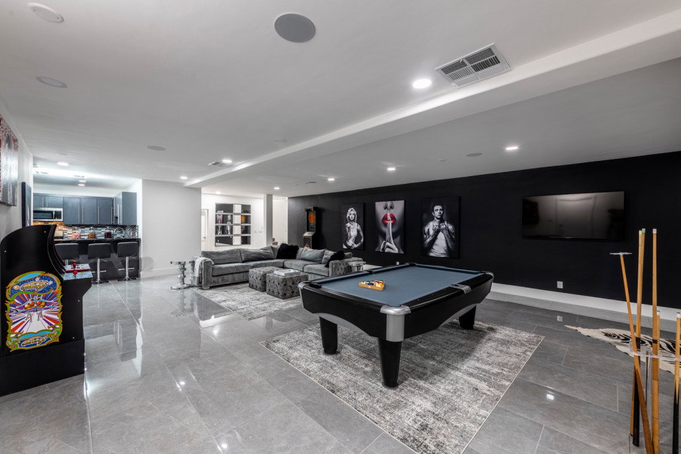 This is an example of an expansive contemporary open concept home theatre in Las Vegas with black walls, ceramic floors, a projector screen and grey floor.
