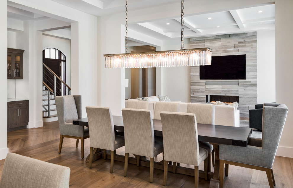 Large transitional dining room in Miami with white walls, medium hardwood floors, a two-sided fireplace, a tile fireplace surround and brown floor.