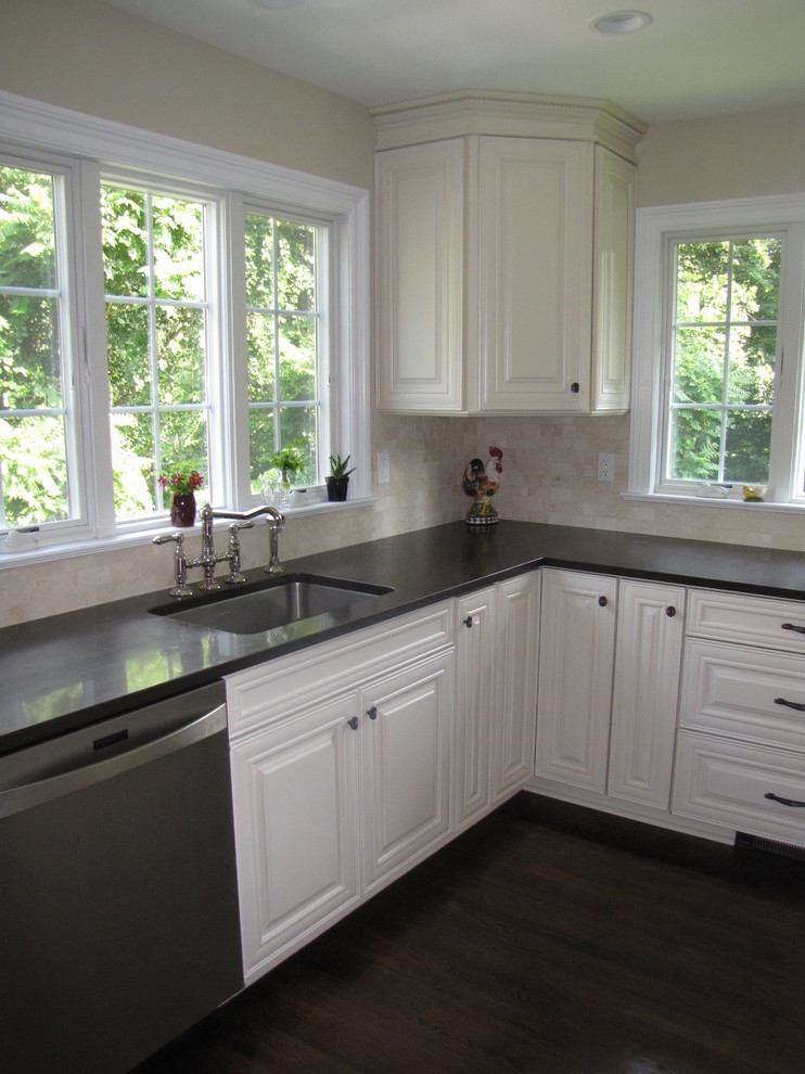 This is an example of a mid-sized traditional u-shaped separate kitchen in New York with a single-bowl sink, raised-panel cabinets, white cabinets, quartz benchtops, beige splashback, stainless steel appliances, dark hardwood floors and no island.