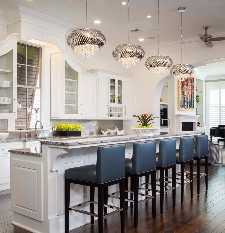 Large transitional galley eat-in kitchen in New Orleans with with island, an undermount sink, raised-panel cabinets, white cabinets, granite benchtops, beige splashback, stone tile splashback, stainless steel appliances and dark hardwood floors.