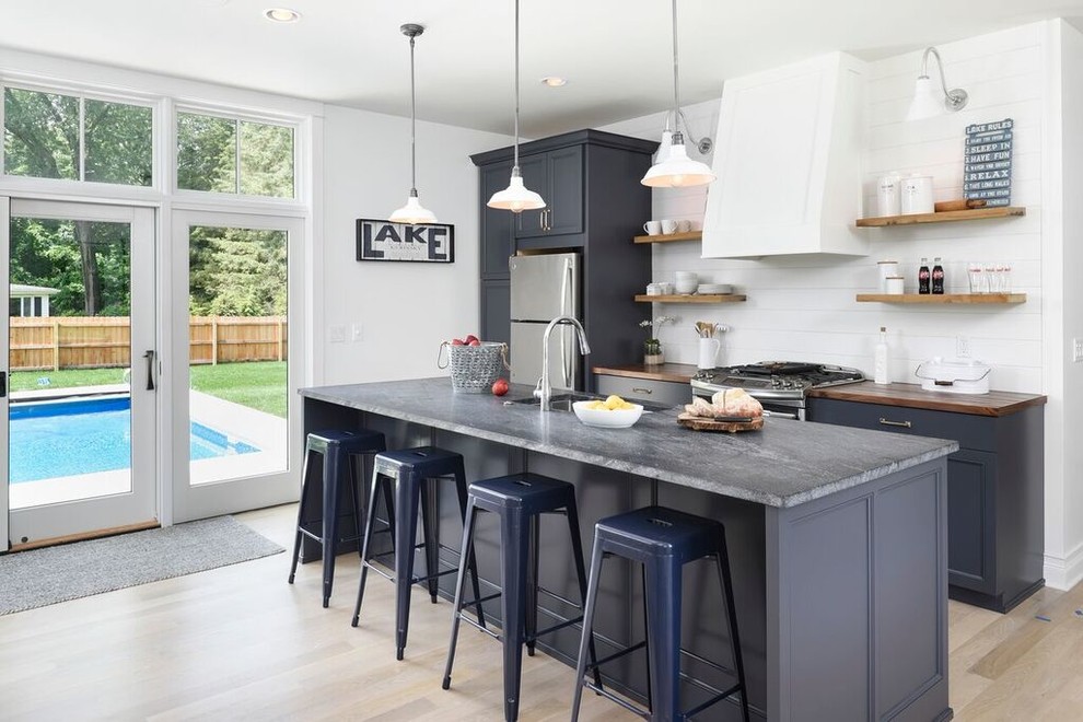 Beach style kitchen in Chicago with an undermount sink, open cabinets, medium wood cabinets, stainless steel appliances, light hardwood floors and with island.