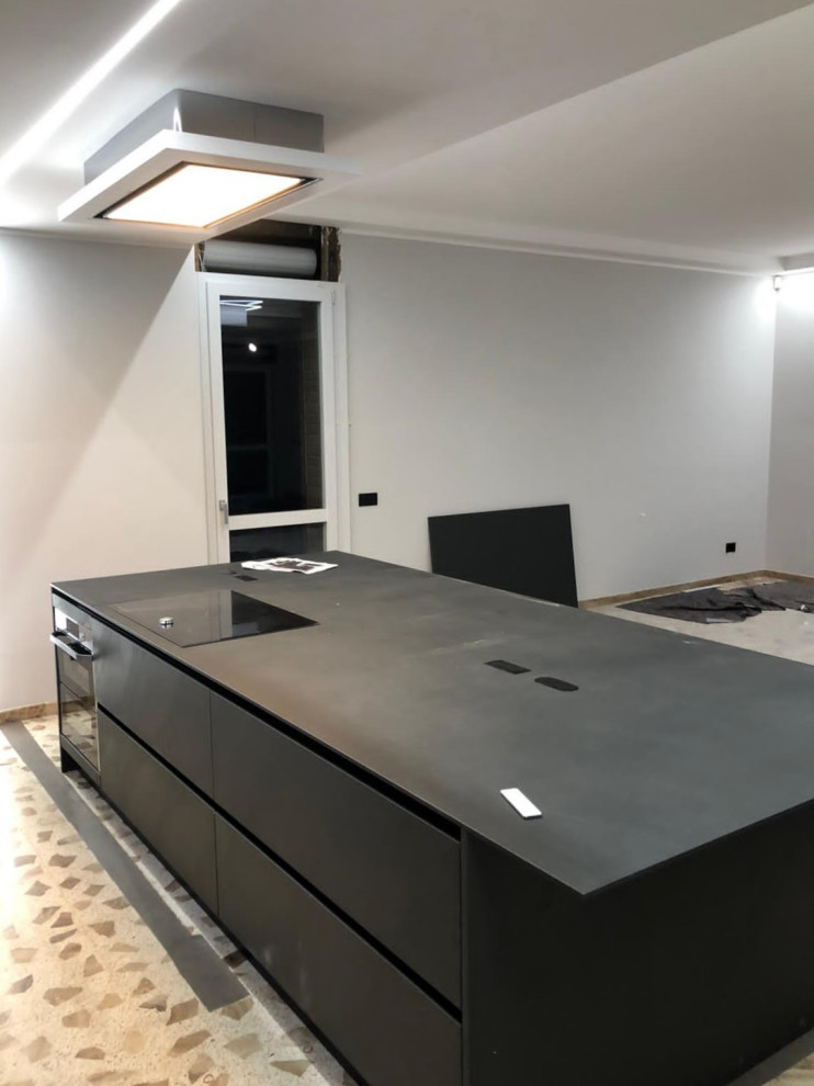 Design ideas for a large contemporary galley open plan kitchen in Other with a submerged sink, glass-front cabinets, black cabinets, tile countertops, black appliances, an island, black worktops and a drop ceiling.