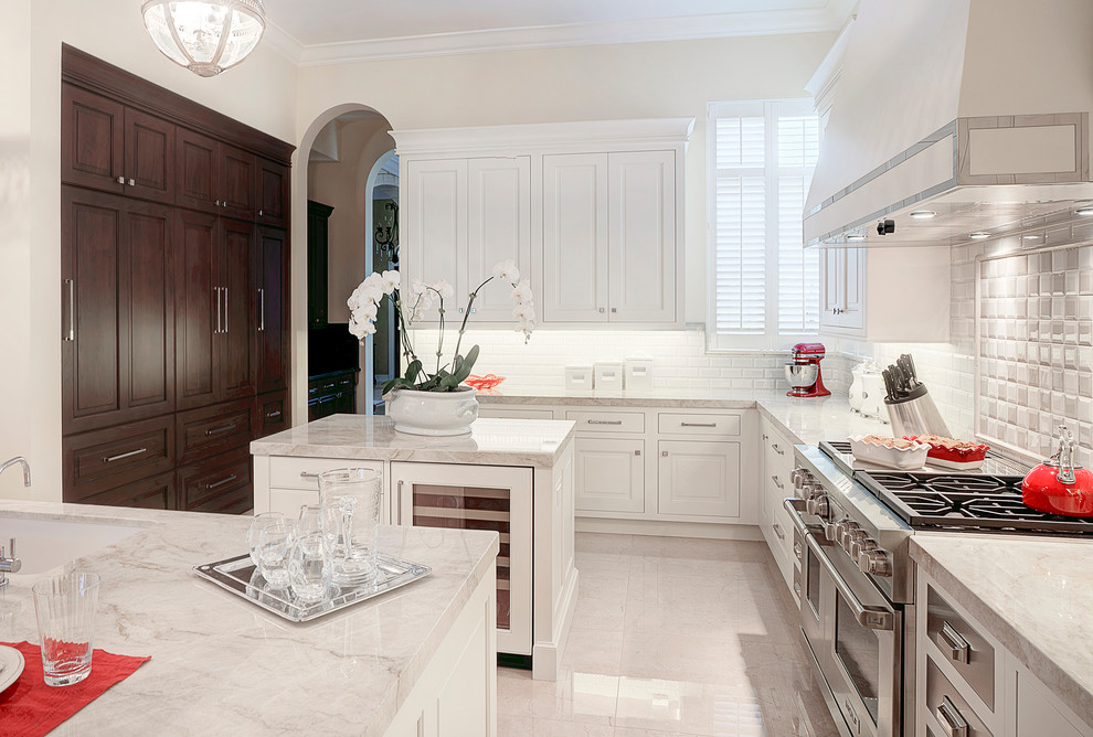 This is an example of a large traditional kitchen in Miami with a single-bowl sink, white cabinets, quartzite benchtops, white splashback, subway tile splashback, panelled appliances, porcelain floors, multiple islands and raised-panel cabinets.