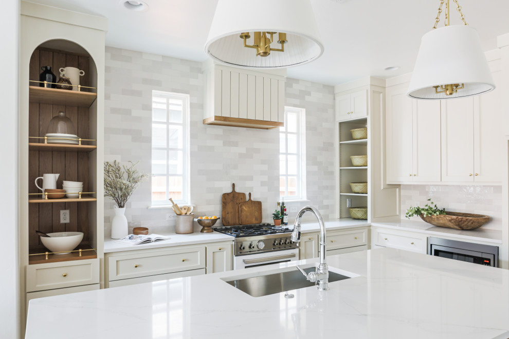 Photo of a mid-sized l-shaped open plan kitchen in Oklahoma City with an undermount sink, shaker cabinets, beige cabinets, quartz benchtops, white splashback, porcelain splashback, white appliances, light hardwood floors, with island, beige floor and white benchtop.