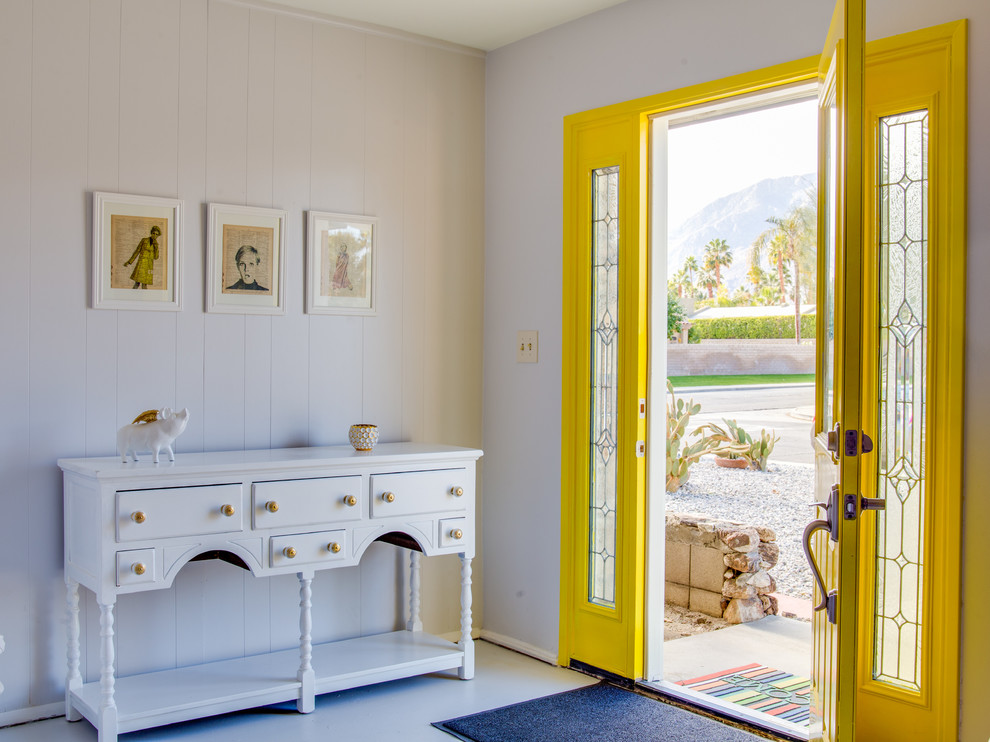 Small midcentury foyer in San Francisco with grey walls, concrete floors, a single front door and a yellow front door.