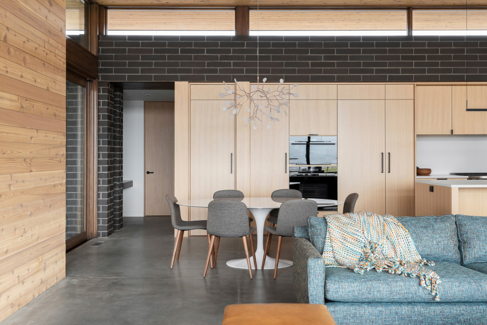 На фото: гостиная-столовая в стиле модернизм с белыми стенами, бетонным полом, серым полом, деревянным потолком и кирпичными стенами