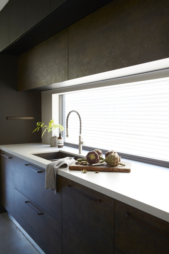 This is an example of a large contemporary galley open plan kitchen in Sydney with a double-bowl sink, flat-panel cabinets, black cabinets, quartz benchtops, stainless steel appliances, concrete floors, with island and grey floor.