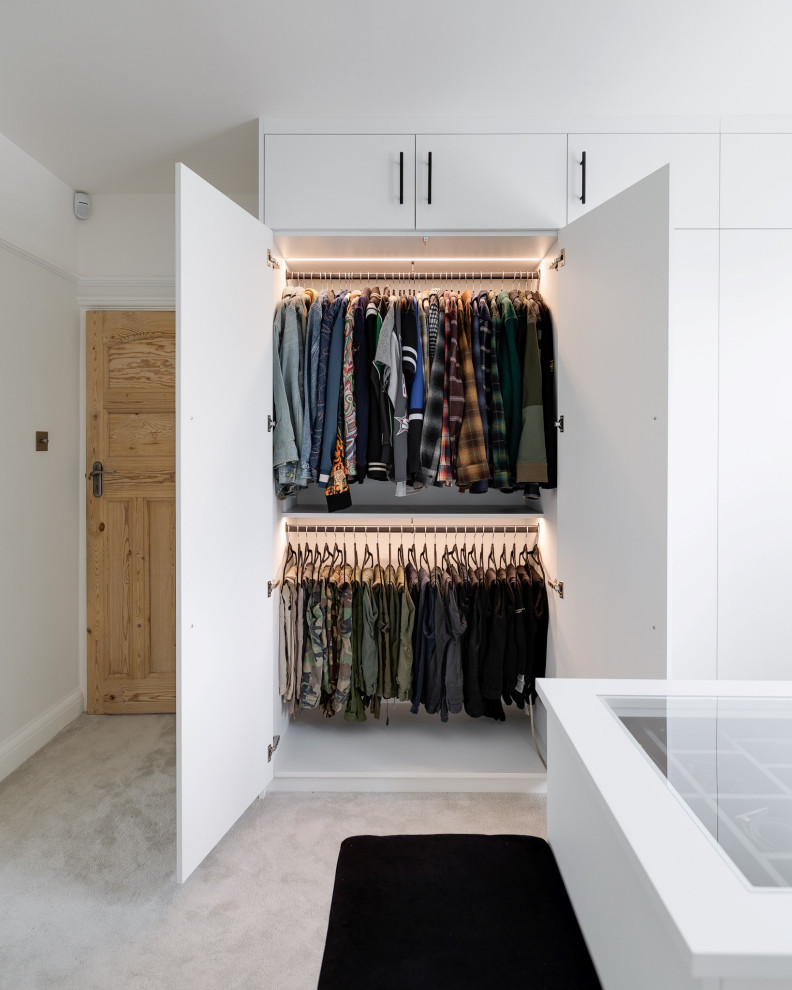 Mittelgroßer Moderner Begehbarer Kleiderschrank mit flächenbündigen Schrankfronten, weißen Schränken, Teppichboden und grauem Boden in Hertfordshire