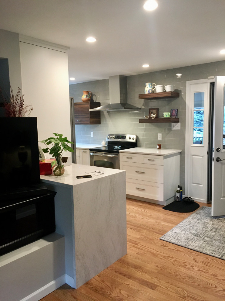 Inspiration for a small transitional u-shaped medium tone wood floor and brown floor enclosed kitchen remodel in Denver with a drop-in sink, shaker cabinets, white cabinets, quartz countertops, gray backsplash, subway tile backsplash, stainless steel appliances, a peninsula and white countertops