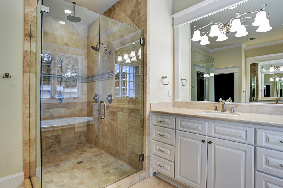 Mid-sized traditional master bathroom in Houston with an undermount sink, raised-panel cabinets, limestone benchtops, a drop-in tub, an alcove shower, a one-piece toilet, beige tile, stone tile, brown walls and limestone floors.