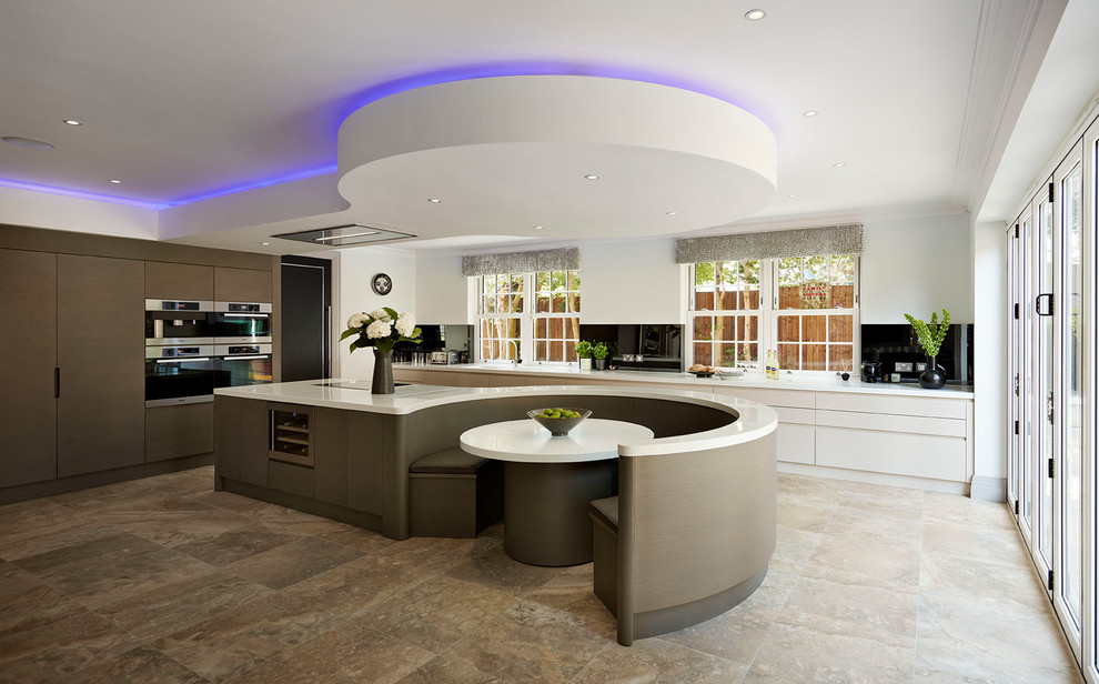 This is an example of an expansive contemporary open plan kitchen in Other with a drop-in sink, solid surface benchtops, black appliances and with island.
