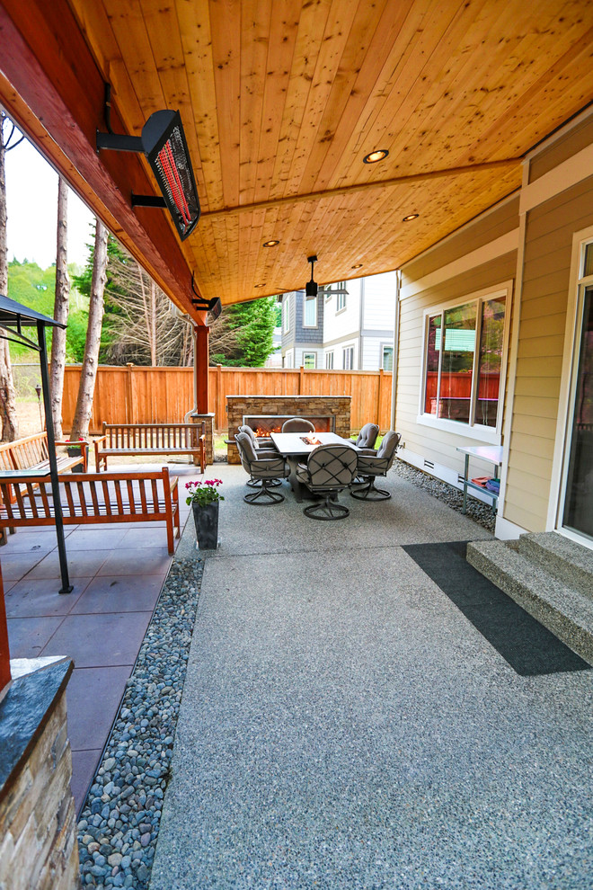 Mid-sized arts and crafts backyard patio in Seattle with with fireplace, concrete pavers and a roof extension.