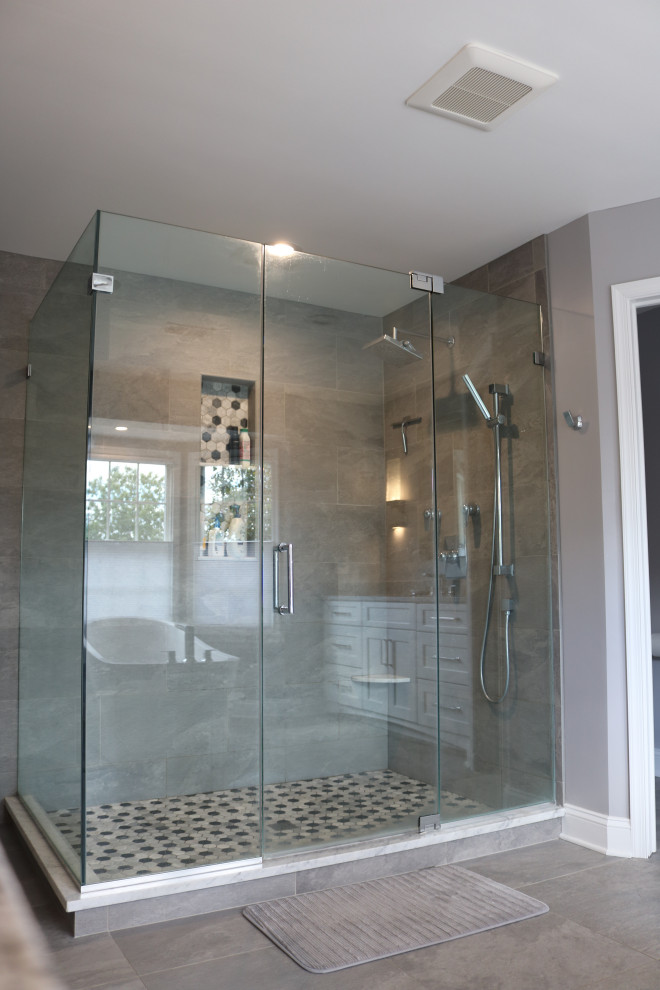 Inspiration for a large transitional master gray tile and porcelain tile porcelain tile, gray floor and single-sink freestanding bathtub remodel in New York with shaker cabinets, white cabinets, an undermount sink, quartz countertops, a hinged shower door, gray countertops and a built-in vanity