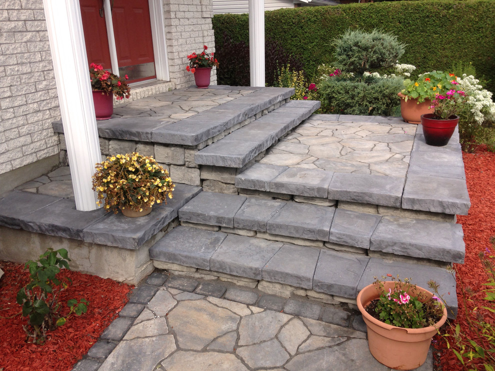 This is an example of a mid-sized modern front yard verandah in Ottawa with a roof extension and natural stone pavers.