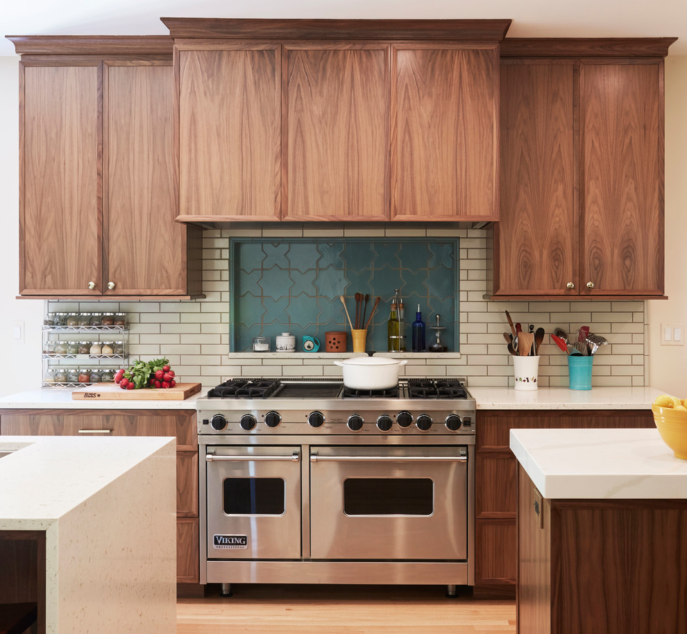 This is an example of a transitional galley eat-in kitchen in Chicago with medium wood cabinets, quartz benchtops, beige splashback, subway tile splashback, light hardwood floors, multiple islands, white benchtop, recessed-panel cabinets and beige floor.