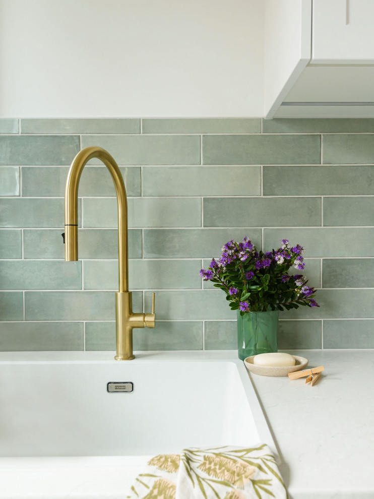 Mid-sized transitional galley dedicated laundry room in Melbourne with a single-bowl sink, shaker cabinets, white cabinets, laminate benchtops, green splashback, subway tile splashback, white walls, vinyl floors, a side-by-side washer and dryer, brown floor and grey benchtop.