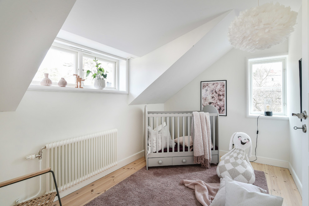 Inspiration for a scandinavian nursery for girls in Stockholm with white walls and light hardwood floors.