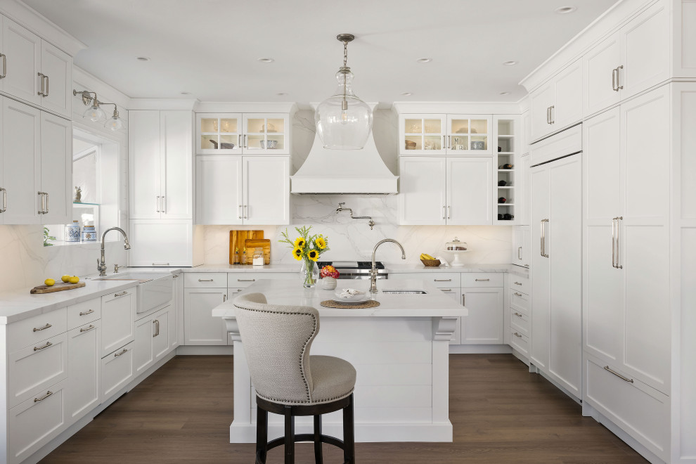 Exempel på ett mellanstort klassiskt vit vitt kök, med en rustik diskho, luckor med infälld panel, vita skåp, bänkskiva i kvarts, vitt stänkskydd, integrerade vitvaror, vinylgolv, en köksö och brunt golv