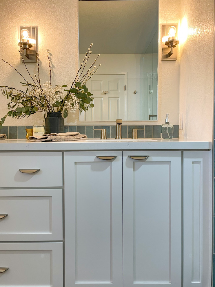 Пример оригинального дизайна: большая главная ванная комната в стиле неоклассика (современная классика) с фасадами в стиле шейкер, белыми фасадами, душем в нише, синей плиткой, керамогранитной плиткой, белыми стенами, полом из керамогранита, врезной раковиной, столешницей из искусственного кварца, серым полом, душем с распашными дверями, белой столешницей, сиденьем для душа, тумбой под две раковины, встроенной тумбой и кирпичными стенами
