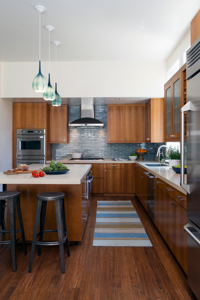 Design ideas for a large modern l-shaped open plan kitchen in San Francisco with a drop-in sink, flat-panel cabinets, medium wood cabinets, quartz benchtops, blue splashback, ceramic splashback, stainless steel appliances, bamboo floors and with island.