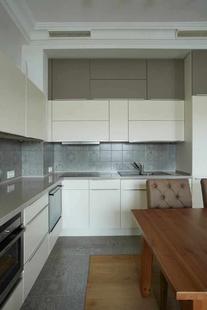 Design ideas for a contemporary l-shaped open plan kitchen in Moscow with flat-panel cabinets and grey splashback.
