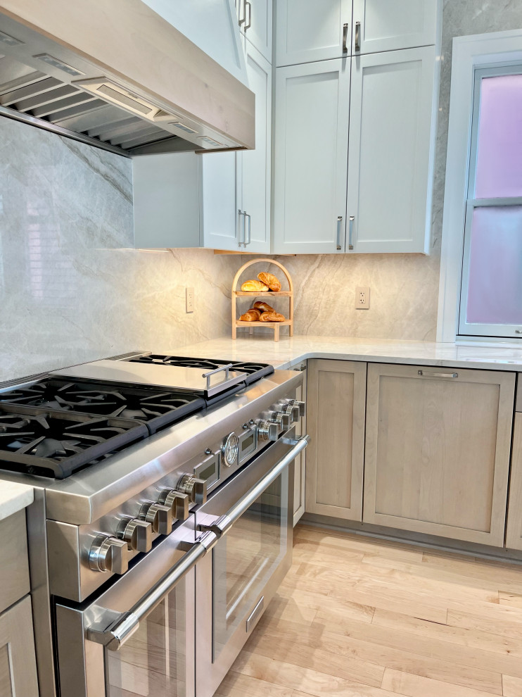 Eat-in kitchen - large modern l-shaped light wood floor and brown floor eat-in kitchen idea with an undermount sink, shaker cabinets, light wood cabinets, quartzite countertops, beige backsplash, stone slab backsplash, stainless steel appliances, an island and beige countertops