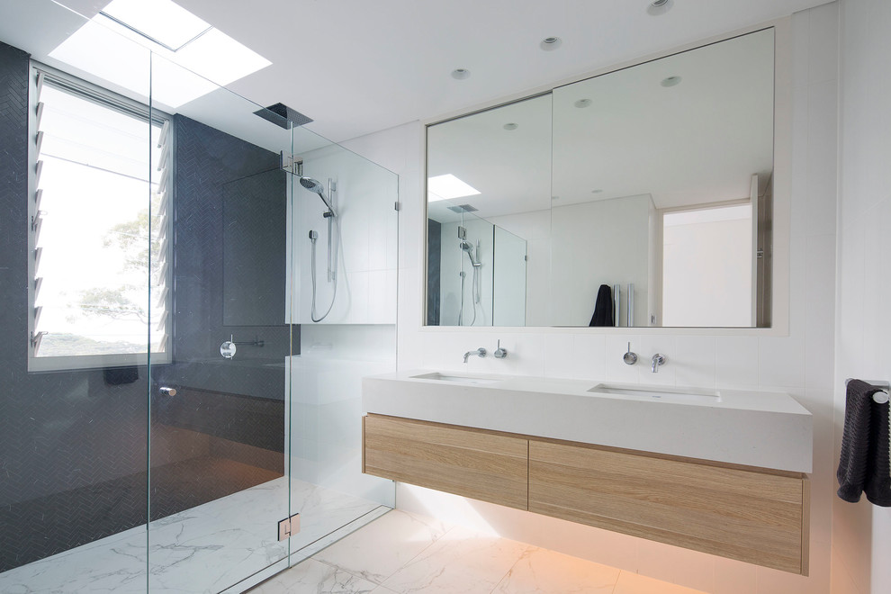 This is an example of a large modern master bathroom in Sydney with a double shower, white tile, ceramic tile, white walls, marble floors, an undermount sink, white floor and a hinged shower door.