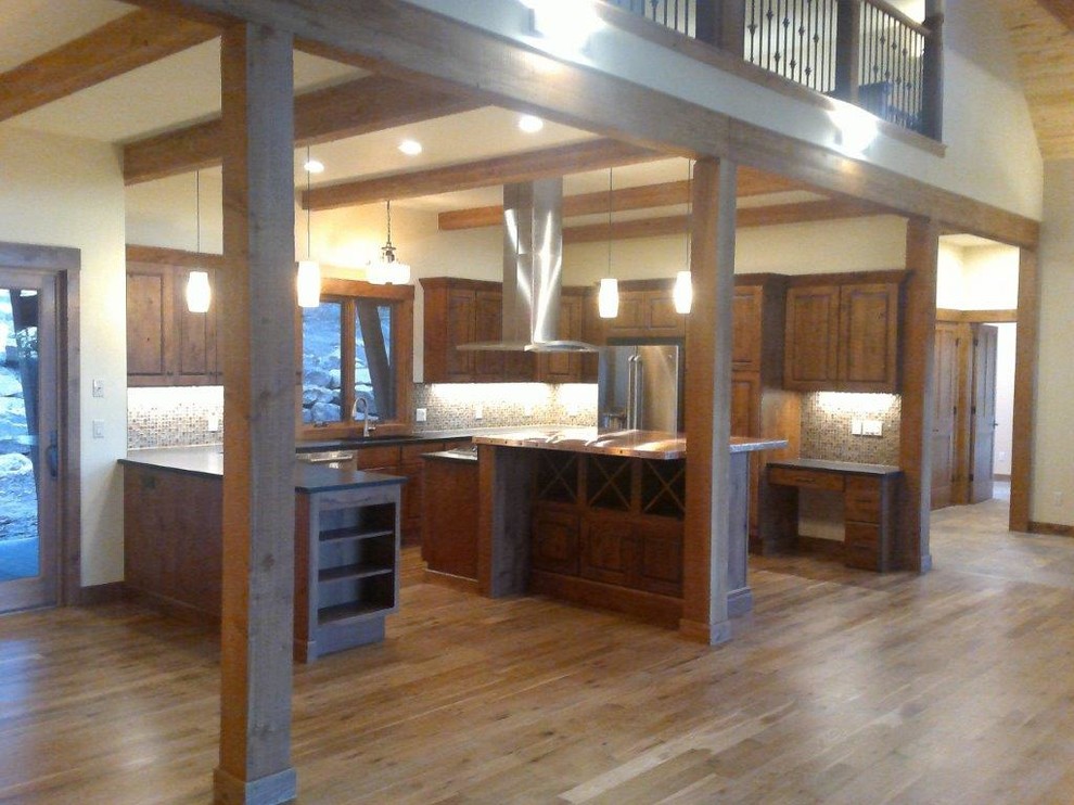 Open concept kitchen - large rustic u-shaped medium tone wood floor and brown floor open concept kitchen idea with an undermount sink, raised-panel cabinets, dark wood cabinets, multicolored backsplash, glass tile backsplash, stainless steel appliances and an island