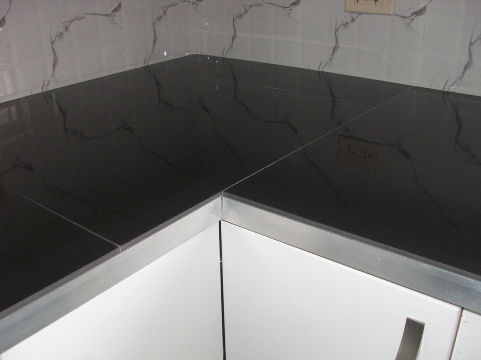 Example of a mid-sized trendy u-shaped kitchen pantry design with a double-bowl sink, flat-panel cabinets, white cabinets, quartz countertops, white backsplash, ceramic backsplash, stainless steel appliances and no island