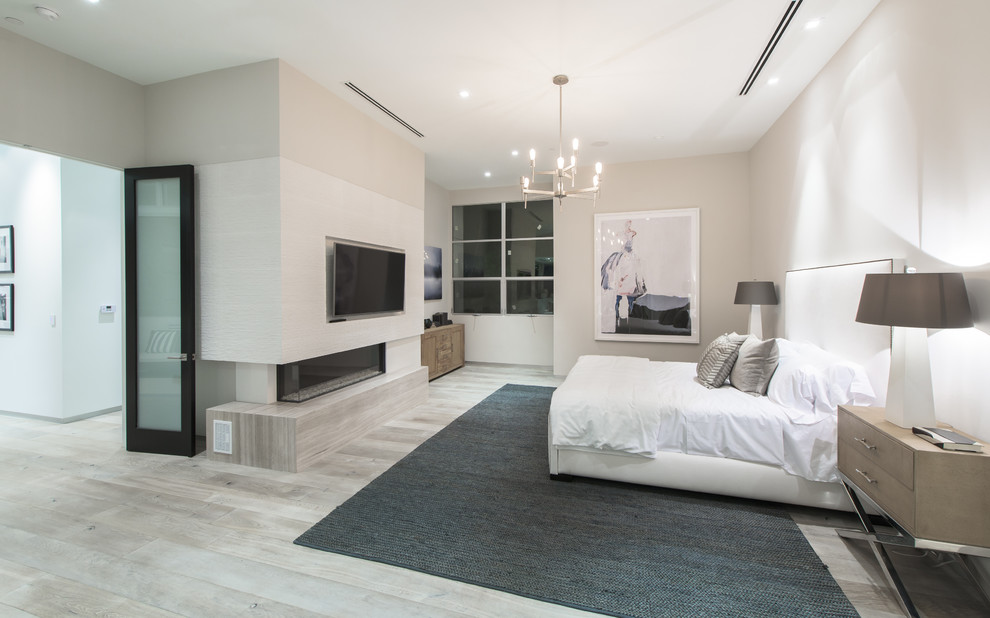 Inspiration for a contemporary master bedroom in Los Angeles with white walls, light hardwood floors, a ribbon fireplace, a concrete fireplace surround and beige floor.