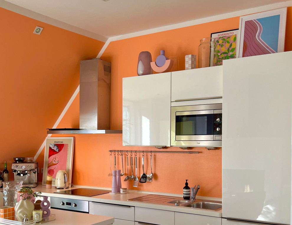 Idéer för att renovera ett mellanstort funkis vit vitt kök, med en integrerad diskho, släta luckor, vita skåp, träbänkskiva, orange stänkskydd, rostfria vitvaror och en köksö