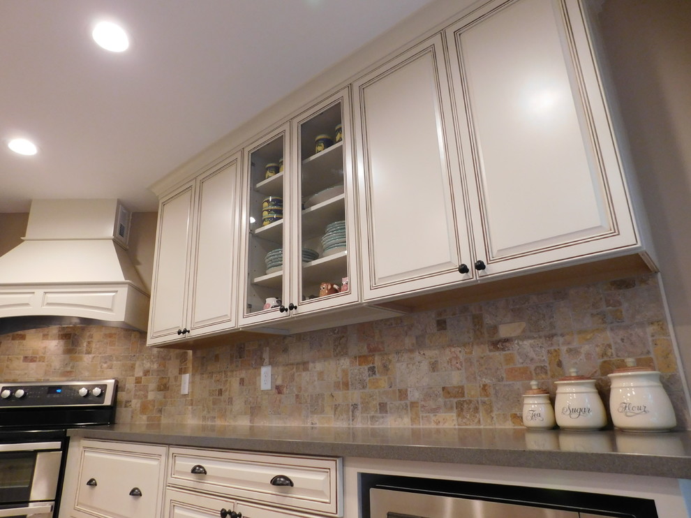 Mid-sized transitional galley vinyl floor enclosed kitchen photo with a farmhouse sink, raised-panel cabinets, beige cabinets, solid surface countertops, multicolored backsplash, stone tile backsplash, stainless steel appliances and no island
