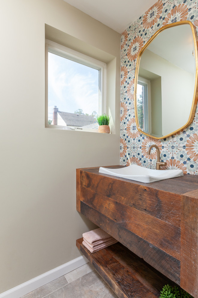 Photo of a small country 3/4 bathroom in New York with flat-panel cabinets, brown cabinets, multi-coloured tile, ceramic tile, beige walls, ceramic floors, a drop-in sink, wood benchtops, beige floor, brown benchtops, a single vanity and a floating vanity.