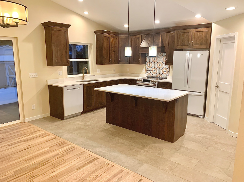 This is an example of a large arts and crafts l-shaped open plan kitchen in Denver with an undermount sink, shaker cabinets, medium wood cabinets, quartz benchtops, multi-coloured splashback, ceramic splashback, white appliances, porcelain floors, with island, beige floor and white benchtop.
