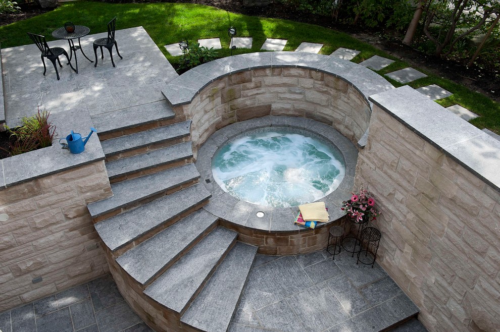 This is an example of a small contemporary backyard round pool in Toronto with a hot tub and concrete pavers.