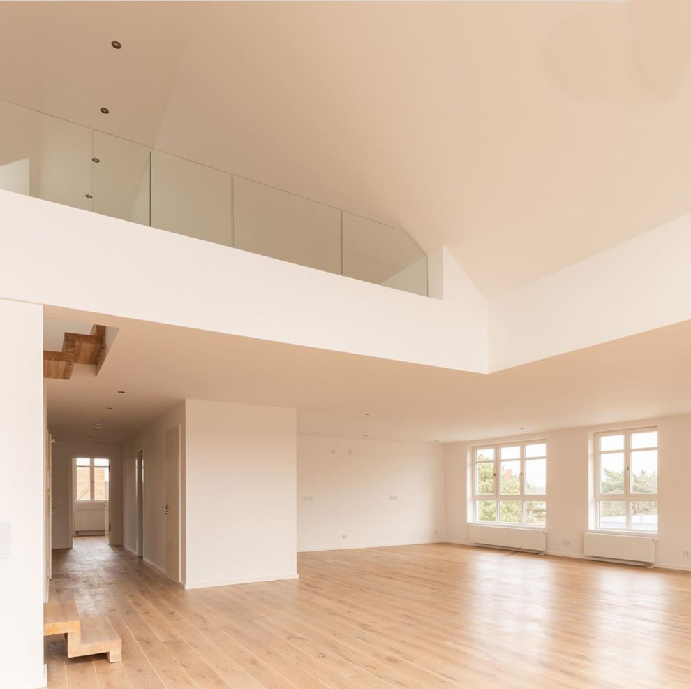 This is an example of a large contemporary open plan games room in Berlin with white walls, painted wood flooring and beige floors.