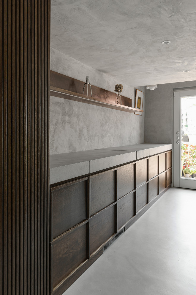 Cette photo montre une petite cuisine linéaire scandinave en bois foncé fermée avec un plan de travail en béton, une crédence grise, un sol gris, un plan de travail gris, sol en béton ciré et aucun îlot.