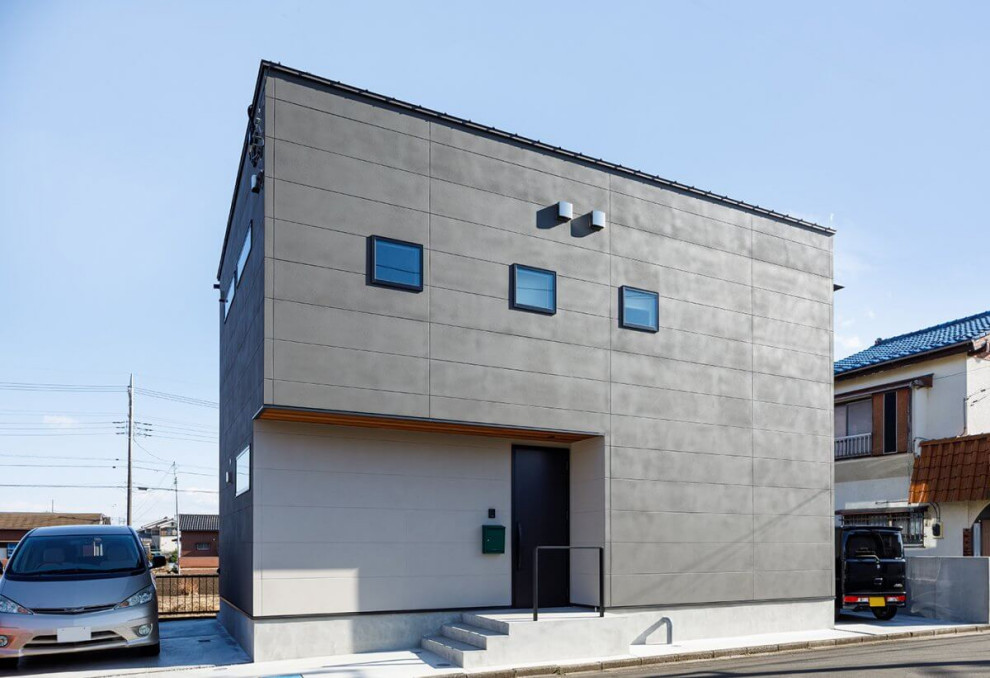 Cette photo montre une petite façade de maison grise industrielle à un étage avec un revêtement mixte, un toit en appentis, un toit en métal et un toit noir.