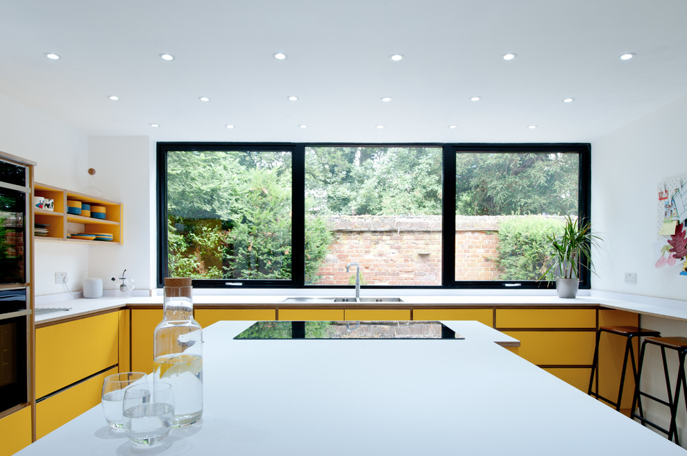 Design ideas for a medium sized contemporary l-shaped kitchen/diner in London with flat-panel cabinets, yellow cabinets, laminate countertops, an island and white worktops.