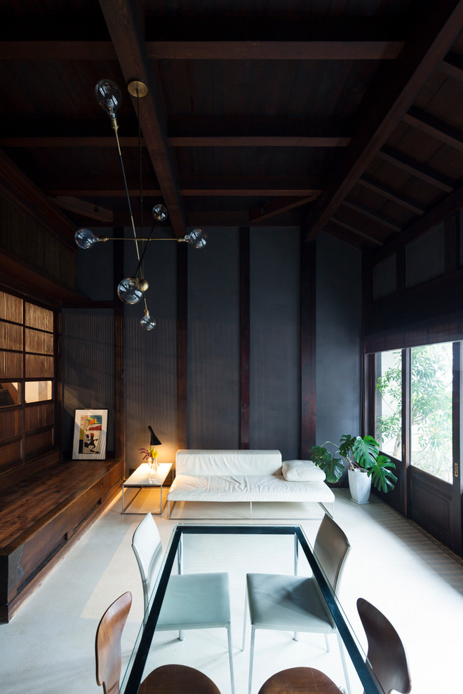This is an example of a contemporary open concept living room in Tokyo with black walls, concrete floors and no fireplace.