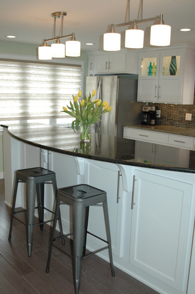 Mid-sized transitional l-shaped medium tone wood floor and brown floor enclosed kitchen photo in Boston with recessed-panel cabinets, white cabinets, multicolored backsplash, an island, an undermount sink, granite countertops, glass tile backsplash and stainless steel appliances