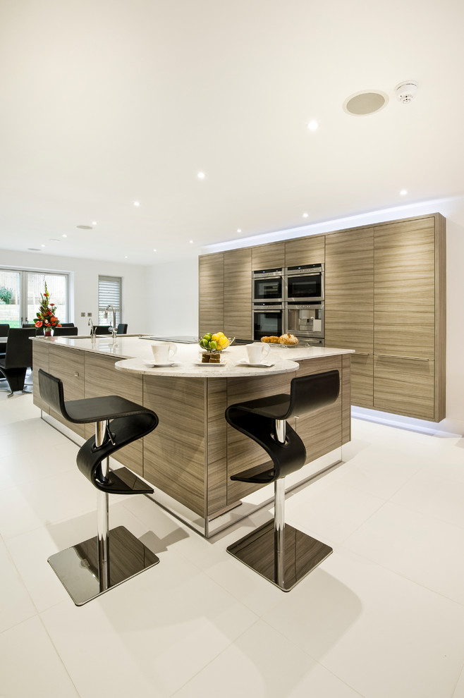 This is an example of a mid-sized contemporary galley eat-in kitchen in West Midlands with flat-panel cabinets, medium wood cabinets, panelled appliances and with island.