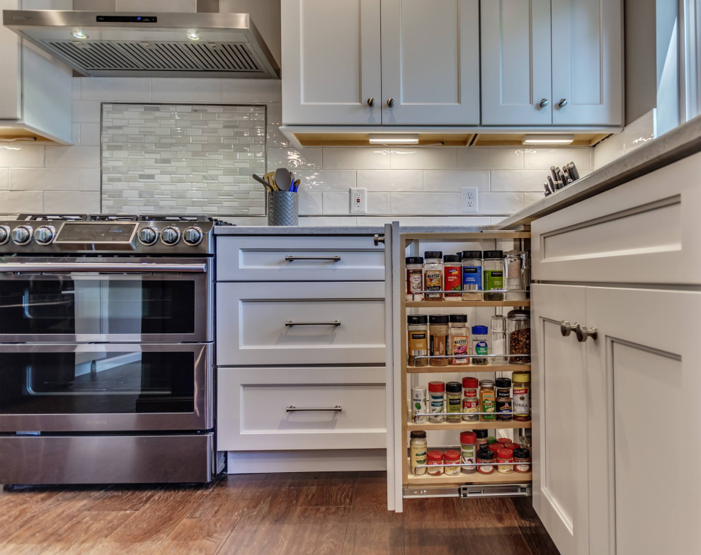 Eat-in kitchen - mid-sized transitional u-shaped brown floor eat-in kitchen idea in St Louis with white cabinets, white backsplash, subway tile backsplash, stainless steel appliances, an island, granite countertops and multicolored countertops