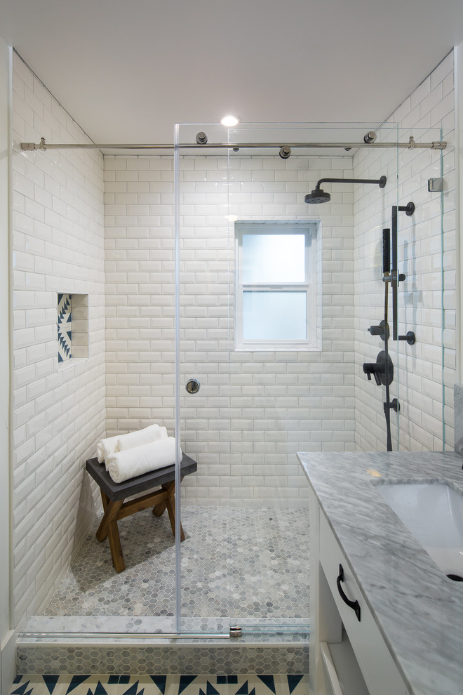 Photo of a mid-sized eclectic master bathroom in San Francisco with flat-panel cabinets, white cabinets, an alcove shower, a one-piece toilet, white tile, ceramic tile, white walls, light hardwood floors, an undermount sink, marble benchtops and a sliding shower screen.