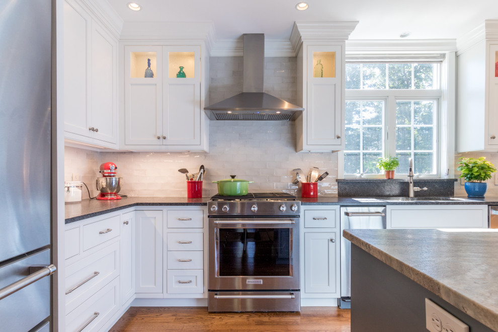 Inspiration for a transitional l-shaped kitchen remodel with white cabinets, granite countertops, white backsplash, stainless steel appliances, an island and multicolored countertops