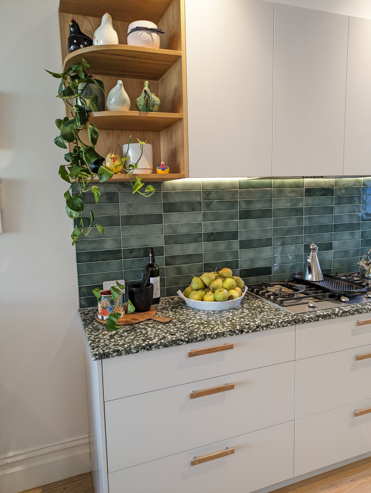 Inspiration for a large modern open plan kitchen in Melbourne with an undermount sink, flat-panel cabinets, green cabinets, quartz benchtops, green splashback, ceramic splashback, stainless steel appliances, light hardwood floors, with island and green benchtop.