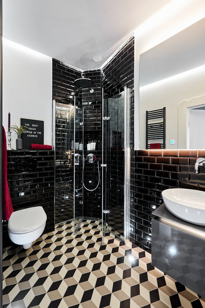 This is an example of a small contemporary 3/4 bathroom in Munich with grey cabinets, a corner shower, a wall-mount toilet, black tile, subway tile, white walls, a vessel sink, multi-coloured floor, a hinged shower door, grey benchtops and flat-panel cabinets.