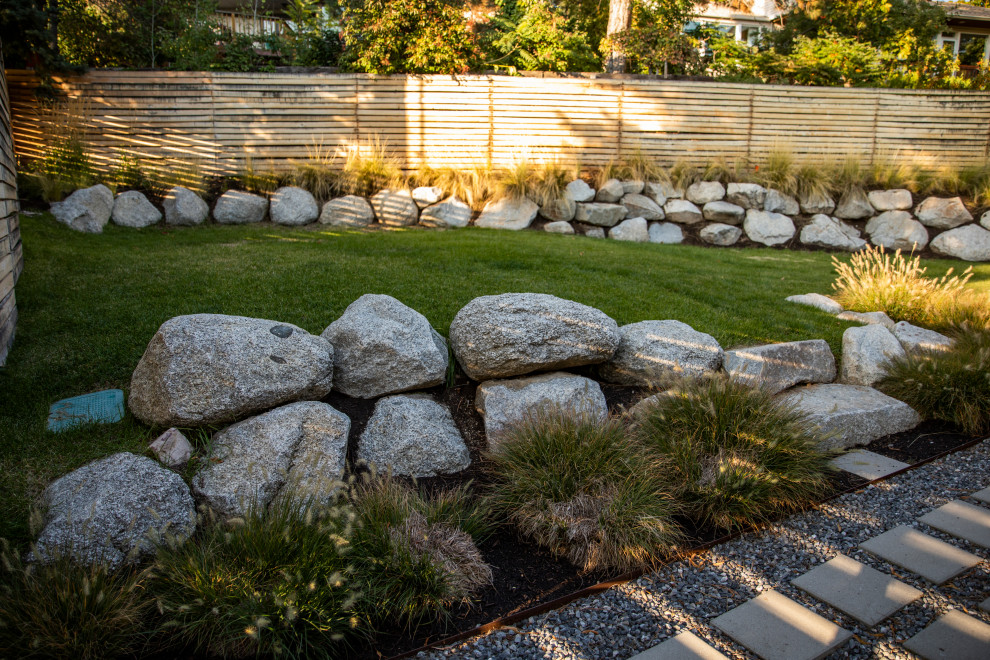 Стильный дизайн: участок и сад среднего размера на заднем дворе в современном стиле с камнем в ландшафтном дизайне, мощением тротуарной плиткой и с деревянным забором - последний тренд