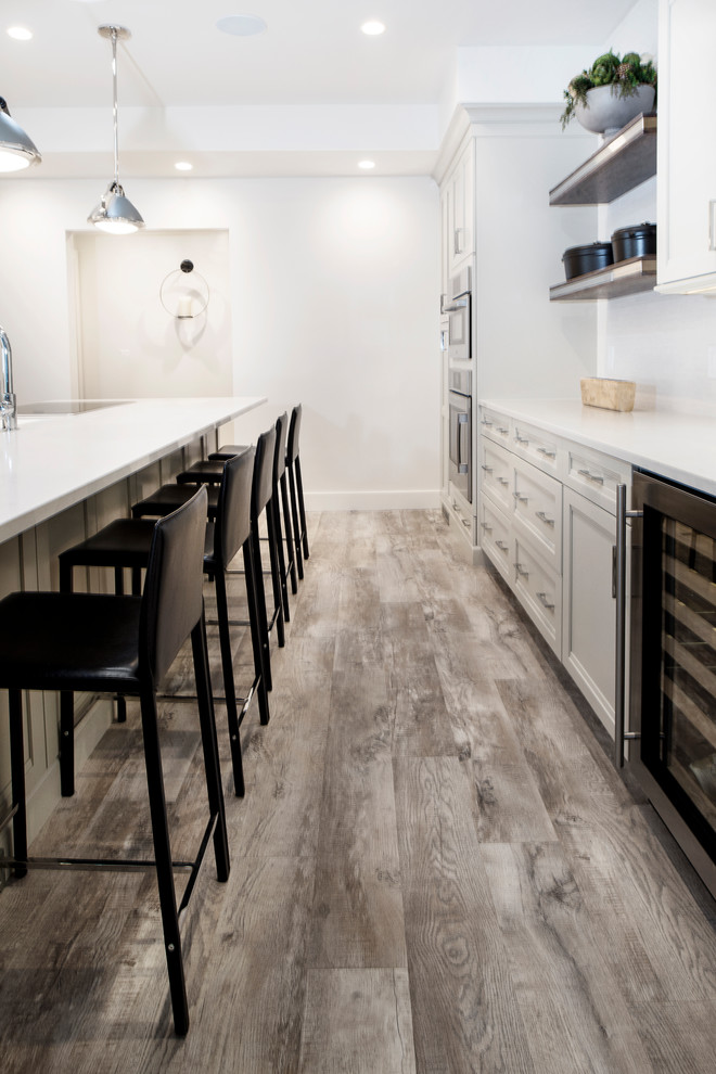 Mid-sized transitional single-wall vinyl floor and brown floor eat-in kitchen photo with an undermount sink, quartzite countertops, white backsplash, stainless steel appliances, an island, shaker cabinets, gray cabinets and porcelain backsplash
